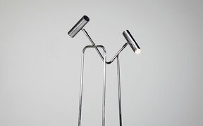 Moderni, kromattu lattiavalaisin, jossa kaksi säädettävää sylinterivalopäätä valkoista taustaa vasten.