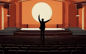 Silhouette of a person with raised arms standing in an empty auditorium facing a large round light on the stage.