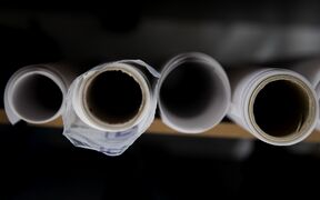 Five rolls of white paper viewed from the top, placed on a wooden surface.