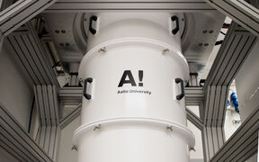 Valkoinen sylinterimäinen kone, jossa 'Aalto University' logo teollisuusympäristössä.