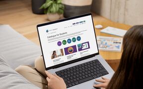 Sohvalla istuva henkilö selaa harmaalla kannettavalla värikästä verkko-opiskelijaluetteloa