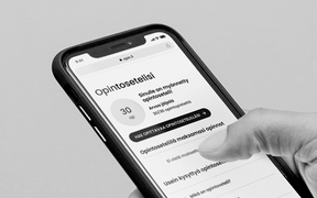 Käsi pitelee mustaa älypuhelinta, jossa auki opintosetelisovellus mustavalkoisena.