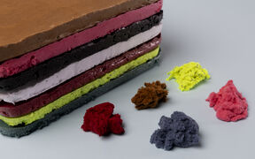 Multicoloured layered foam block with matching fluffy chunks scattered on a light surface