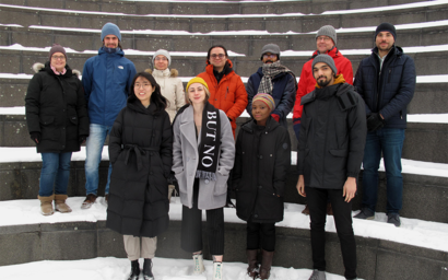 A group of people in coats standing outside on snowy staircase