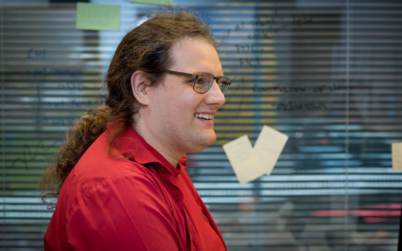 Matti Nelimarkka istuu sivuttain ja hymyilee katsoen pois kamerasta.