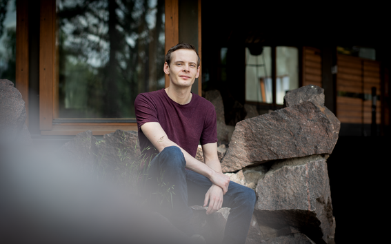 Male student sitting on rocks outside Dipoli building