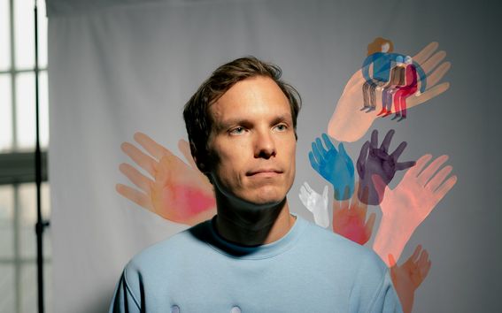 Richard Nordströmillä on kuvassa yllään Helppy-firman logolla varustettu sininen collegepaita. Nordströmin taustalla on kangas, johon on kuvitettu ihmishahmoja ja käsiä. Kuvaaja: Rainer Paananen. Kuvittaja: Satu Kettunen.