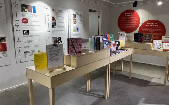 Seinäplansseja ja kirjapöytiä näyttelytilassa. 