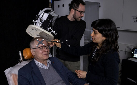 Three persons working with a brain imaging device