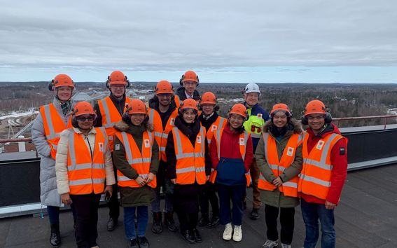 A group of students standing outside on the rooftop of a paper mill.