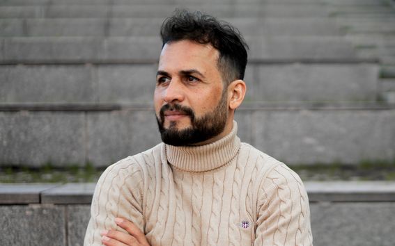 A man sits on stone steps with his arms crossed.