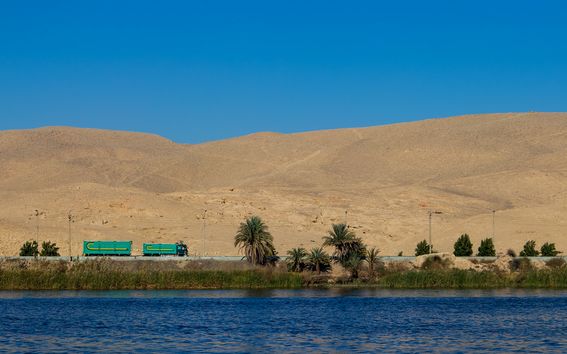 Jokimaisema, jossa taustalla aavikkoa. Välissä kulkee tie, jossa ajaa rekka-auto.