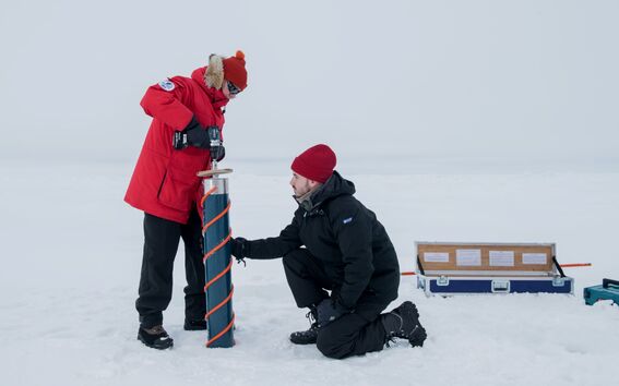 Two researcherss drilling ice