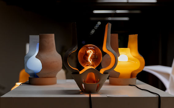 Exhibit of artistic lamps with different coloured lights on a white platform in a dimly lit space.