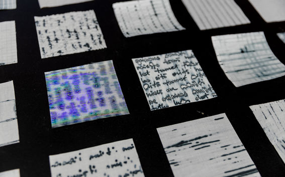 A collection of small fabric squares with various writing and patterns displayed on a dark surface.