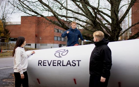 Kolme ihmistä tuulivoimalan siiven luona.