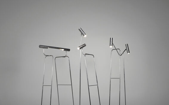 Three modern floor lamps with thin, tall metal stands and cylindrical lights, arranged artistically.