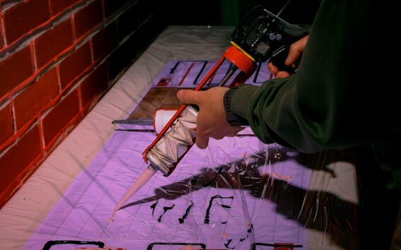 A person uses a caulking gun to apply sealant on a laminated surface near a brick wall.