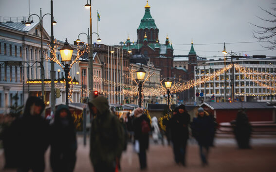 Katujuhla valoineen, käveleviä ihmisiä ja taustalla vihreäkattoinen katedraali.