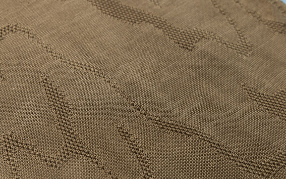 Close-up of brown woven fabric with subtle raised zigzag pattern across the surface