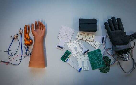 Parts of prosthetic hands and electronics laid out on a light surface for assembly