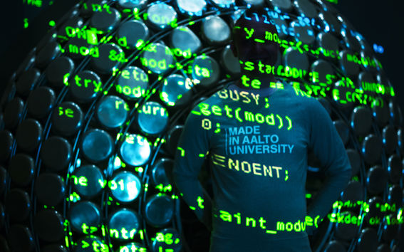 Henkilö seisoo pimeässä ja hänen taustalleen on heijastettu vihreää koodia.