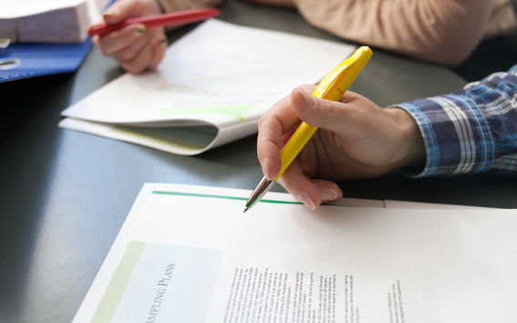 Two people taking notes on an article