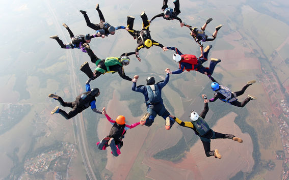 Laskuvarjohyppääjiä muodostelmassa taivaalla