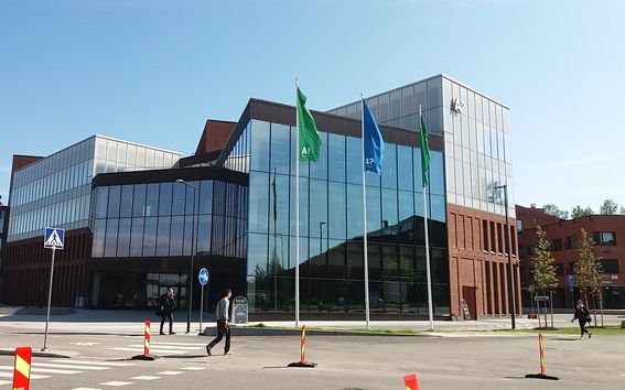 Outside picture of the School of Business building in Otaniemi. Three Aalto Flags swinging in front of the building.