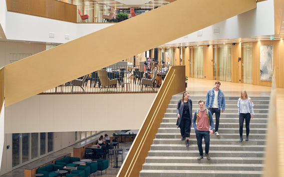 Neljä opiskelijaa laskeutuu portaita valoisassa aulatilassa kampuksella. Kuva: Aalto-yliopisto / Unto Rautio.