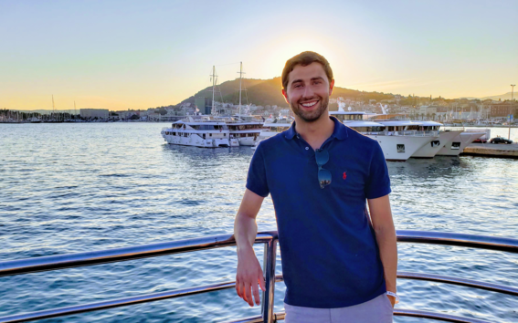 Tyler Spring standing in a harbour at sunset, smiling. 