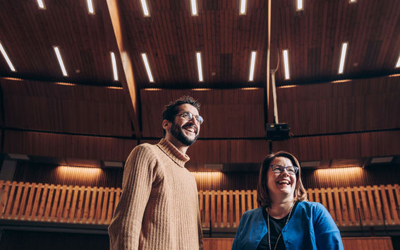Two people standing and laughing in a lecture hall