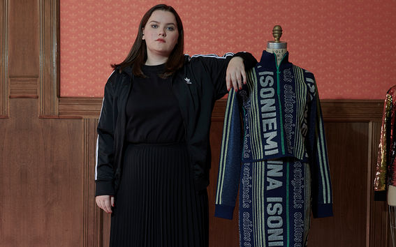 Mustiin pukeutunut Anna Isoniemi seisoo mallinuken vieressä, jolla on hänen suunnittelemansa vaate yllään