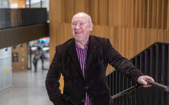 Portaikossa kuvattu mies katsoo kuvaajan ohi vasemmalle ja hymyilee