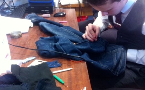 Mies korjaa farkkujaan käsin pöydän ääressä