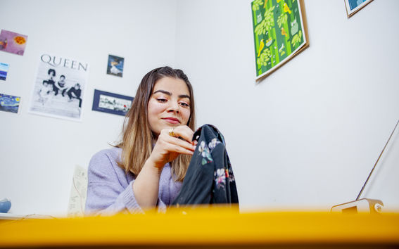 Marium Durrani ompelemassa käsin vaatekappaletta, jossa on kukkakuosi.