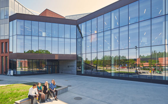 Kauppakorkeakoulu, jonka edustalla istuu neljä opiskelijaa. Kuva: Unto Rautio / Aalto-yliopisto