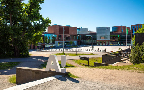 White A! logo standing on the ground with A-bloc and Väre in the background.