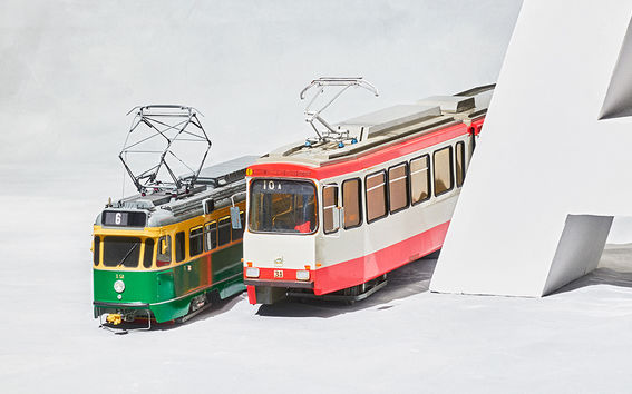 Kuvassa keltavihreä ja punavalkoinen raitiovaunu.