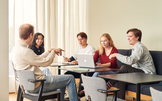 Viiden hengen ryhmä työskentelemässä pöytien äärellä