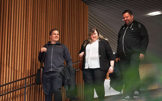 Kolme ihmistä kävelee vierekkäin alas portaita.