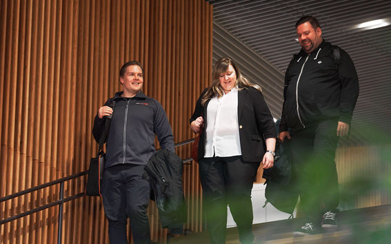 Kolme ihmistä kävelee vierekkäin alas portaita.