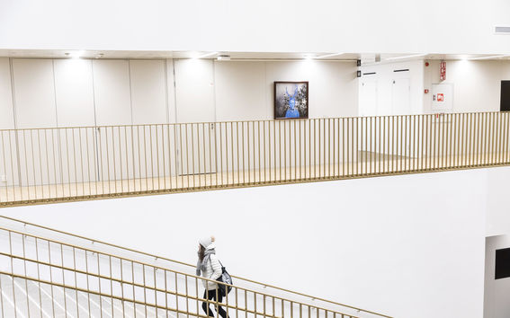 Aalto University School of Business, a student ascending, public art of Risto Suomi on the wall, photo Mikko Raskinen