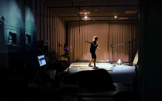 A man in a soundproof studio waving an object to create sound