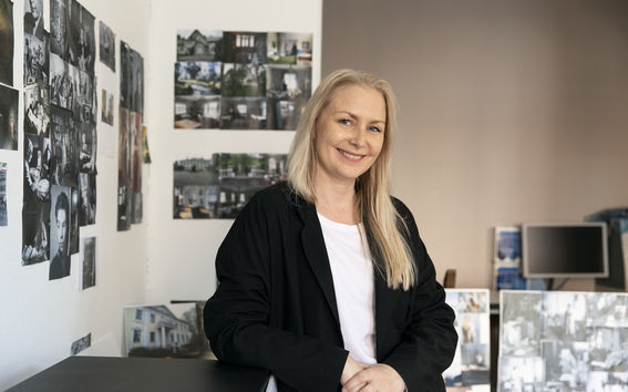 vaaleahiuksinen nainen mustavalkoisessa asussaan katsoo hymyillen suoraan kameraan