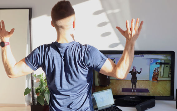 Mies tekee taukoliikuntaa kotona television ääressä.