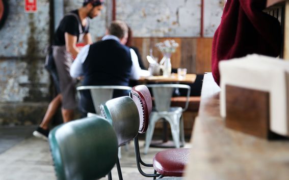 Tuoleja ravintolatilassa, taustalla asiakaspalvelutilanne