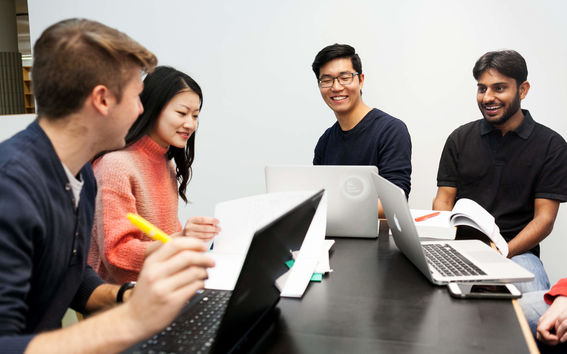 Four students at a table with laptops