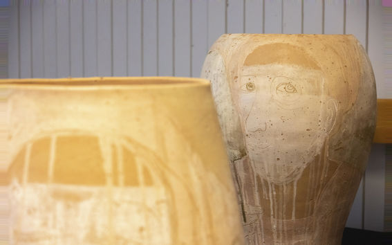 Two ceramic pots in shot, one in the back and the second seen partially at the very front