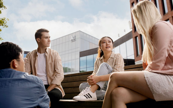 A group of four Aalto students sitting outside Väre discussing about group work